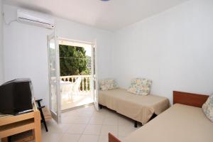 Apartments by the sea Brna, Korcula - 9139 في برنا: غرفة بسرير وتلفزيون وشرفة