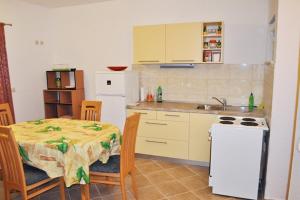 eine Küche mit einem Tisch und einem weißen Kühlschrank in der Unterkunft Apartments by the sea Cove Milna - Zastrazisce, Hvar - 8951 in Zastražišće