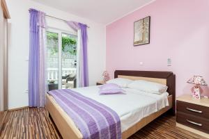 een slaapkamer met een bed en een raam met paarse gordijnen bij Apartments by the sea Brna, Korcula - 9147 in Brna