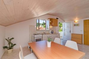 a kitchen with a wooden table and white chairs at Apartments and rooms by the sea Molunat, Dubrovnik - 9102 in Gruda