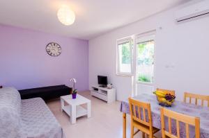 a living room with a table and a clock on the wall at Apartments by the sea Sladjenovici, Dubrovnik - 9012 in Slano