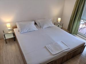 - un grand lit avec des draps et des oreillers blancs dans une chambre dans l'établissement Apartments by the sea Sladjenovici, Dubrovnik - 9012, à Slano