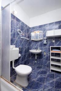 Un baño con azulejos azules, inodoro y lavabo. en Apartments by the sea Brna, Korcula - 9159, en Smokvica