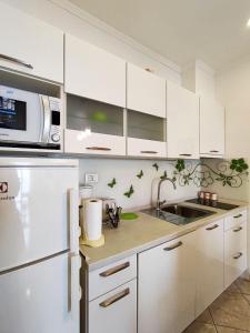 a white kitchen with a sink and a microwave at Apartments with a parking space Vrbica, Dubrovnik - 9008 in Dubrovnik