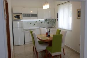 a kitchen with a wooden table and green chairs at Apartments with a parking space Vrbica, Dubrovnik - 9008 in Dubrovnik