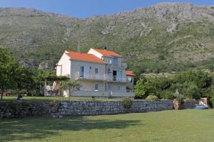 una casa detrás de una pared de piedra con montañas en el fondo en Apartments for families with children Mlini, Dubrovnik - 8970 en Mlini