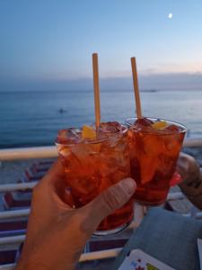 osoba trzymająca dwa drinki w rękach w obiekcie Villa Edoardo con pineta a 250 metri dal mare w mieście Torre Squillace