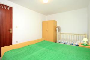 een slaapkamer met een groen bed en een wieg bij Apartment Prigradica 9141b in Blato