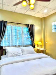 a bedroom with a large white bed with a window at ภูมินทร์โฮมน่าน in Nan
