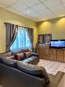 a living room with a leather couch and a flat screen tv at ภูมินทร์โฮมน่าน in Nan
