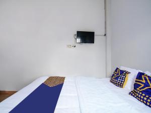 um quarto com uma cama e uma televisão na parede em SPOT ON 91598 Oklahoma Homestay Syariah em Pekanbaru