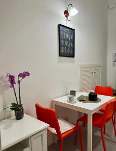una sala da pranzo con tavolo bianco e sedie rosse di CiuriCiuri Home Appartamento storico nel centro di Catania a Catania