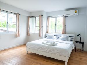 a white bedroom with a large white bed with windows at Art Gallery Apartment@Chiang Mai train station in Chiang Mai