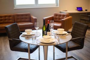 einen Tisch mit Stühlen, Weinflaschen und Gläser in der Unterkunft Hotel Circle Inn in Ramstein-Miesenbach