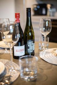 Hotel Circle Inn في رامشتاين-ميزنباخ: زجاجتان من النبيذ تقعان على طاولة مع أكواب