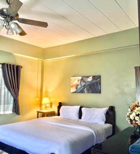 - une chambre avec un lit et un ventilateur de plafond dans l'établissement ภูมินทร์โฮมน่าน, à Nan