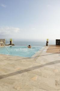 a person in a swimming pool with the ocean in the background at Anamcara Suites in Las Indias