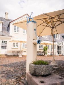 a white and blue fire hydrant next to a white umbrella at Hotel Knudsens Gaard in Odense