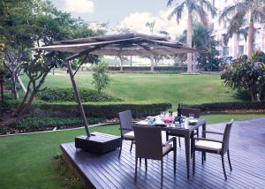 a table and chairs under an umbrella on a wooden deck at The Grand New Delhi in New Delhi