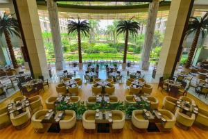 a restaurant with tables and chairs and palm trees at The Grand New Delhi in New Delhi