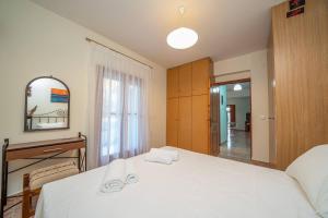 a bedroom with a large white bed and a mirror at Afroditi Holiday Home - Blue Apartment in Svoronata