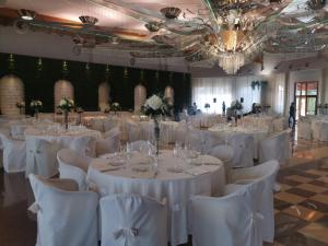 un salón de banquetes con mesas y sillas blancas y una lámpara de araña en Hotel Park Grumentum, en Grumento Nova