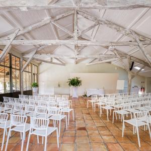 Cette chambre comprend des rangées de chaises et de tables blanches. dans l'établissement Domaine de Boulouch, à Lectoure