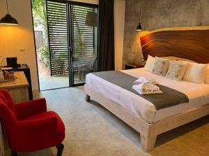 - une chambre avec un lit et une chaise rouge dans l'établissement Little Gem Hotel Tulum La Veleta, à Tulum