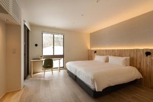 a bedroom with a bed and a desk and a window at Silver Maple Chalet by Hakuba White Fox Company in Hakuba +25 photos