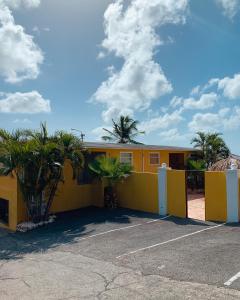 een geel gebouw met palmbomen op een parkeerplaats bij Casa di Caribe in Willemstad +10 foto's
