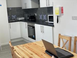 ordenador portátil con mesa de madera en la cocina en Fabulous, Spacious, Newly Refurbished Home close to Heathrow Airport en Hayes