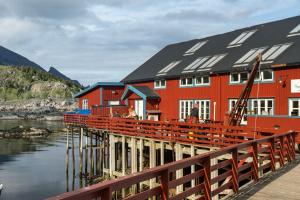 een rood gebouw met zonnepanelen op het water bij Brygga Restaurant and Rooms in Å
