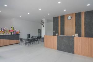 un restaurante con mesas y sillas y un reloj en la pared en Cattail Guest House Pontianak en Pontianak