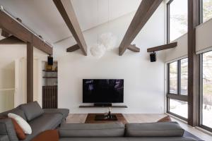 uma sala de estar com um sofá e uma televisão de ecrã plano em Silver Maple Chalet by Hakuba White Fox Company em Hakuba