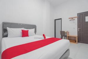 ein Schlafzimmer mit einem großen Bett mit einer roten Decke in der Unterkunft Cattail Guest House Pontianak in Pontianak