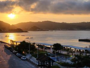 a view of a city with the sun setting over the water at Fuaowo Backpackers Homestay in Nangan