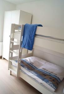ein weißes Etagenbett mit einer Leiter neben einem Fenster in der Unterkunft Heimathafen in Langeoog
