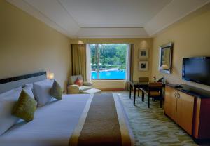 a hotel room with a large bed and a television at The Grand New Delhi in New Delhi