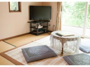 uma sala de estar com uma televisão e uma mesa em Gasthof yell / Vacation STAY 79366 em Kuroiso