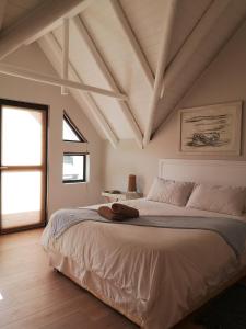 Schlafzimmer mit einem großen weißen Bett und Holzböden in der Unterkunft St Francis Bay House On The Canal in St Francis Bay