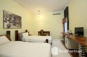 Cette chambre comprend deux lits et une télévision. dans l'établissement Rumah Palagan Yogyakarta RedPartner, à Ngaglik