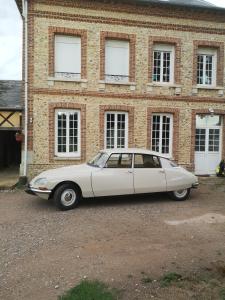 een witte auto geparkeerd voor een bakstenen gebouw bij Les Chambres de Thiergeville in Thiergeville