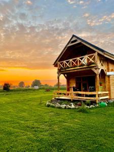 eine Holzhütte auf einem Feld mit Sonnenuntergang im Hintergrund in der Unterkunft Gabel&Jurgen in Mirsk