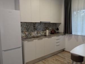 a kitchen with white cabinets and a sink at Apartament lângă Catedrală in Câmpulung Moldovenesc +15 photos