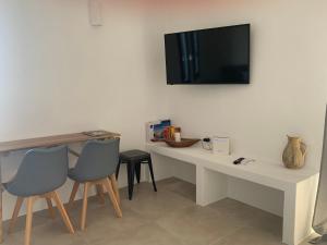 a desk with two chairs and a television on a wall at Paros-Memories-Neubau-Villen, Sportpool in Aspro Chorio Paros