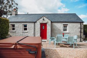 a small white cottage with a red door and chairs at Lizzie's Cottage in Drumaroad
