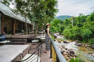 a woman standing on a balcony overlooking a river at Green Valley Veal Pouch in Kampot