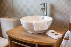 a bathroom with a white bowl sink on a wooden counter at Stewarts Resort Lodge 8 in St. Andrews