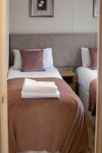 a hotel room with two beds with towels on the bed at Stewarts Resort Lodge 8 in St Andrews