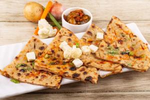 a plate of food with pizza and vegetables on a table at Trimrooms Shree Mata Palace, Katra Bus Stand in Katra